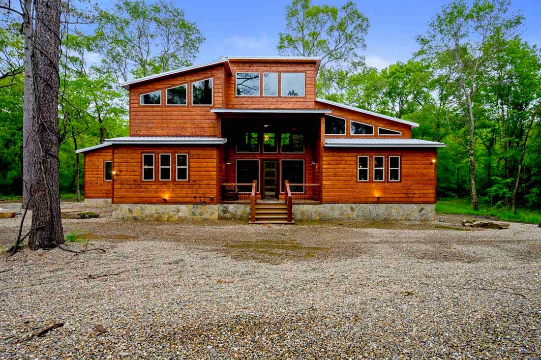 Front of log modern cabin with large driveway