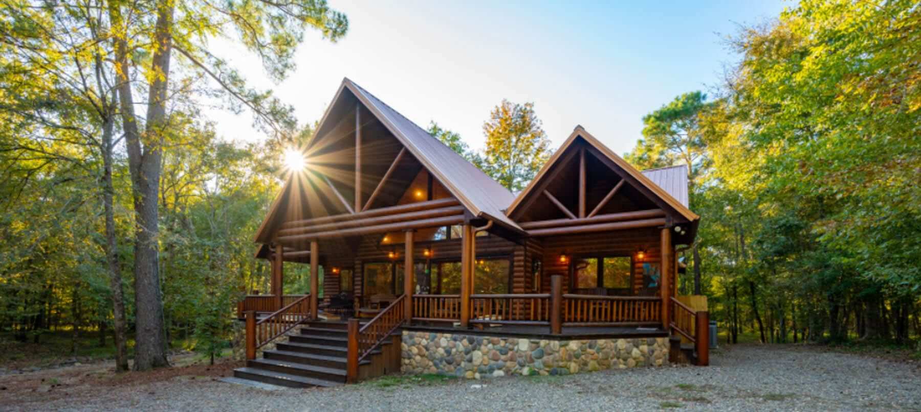 A rustic log cabin surrounded by trees with sunlight streaming through the roof.