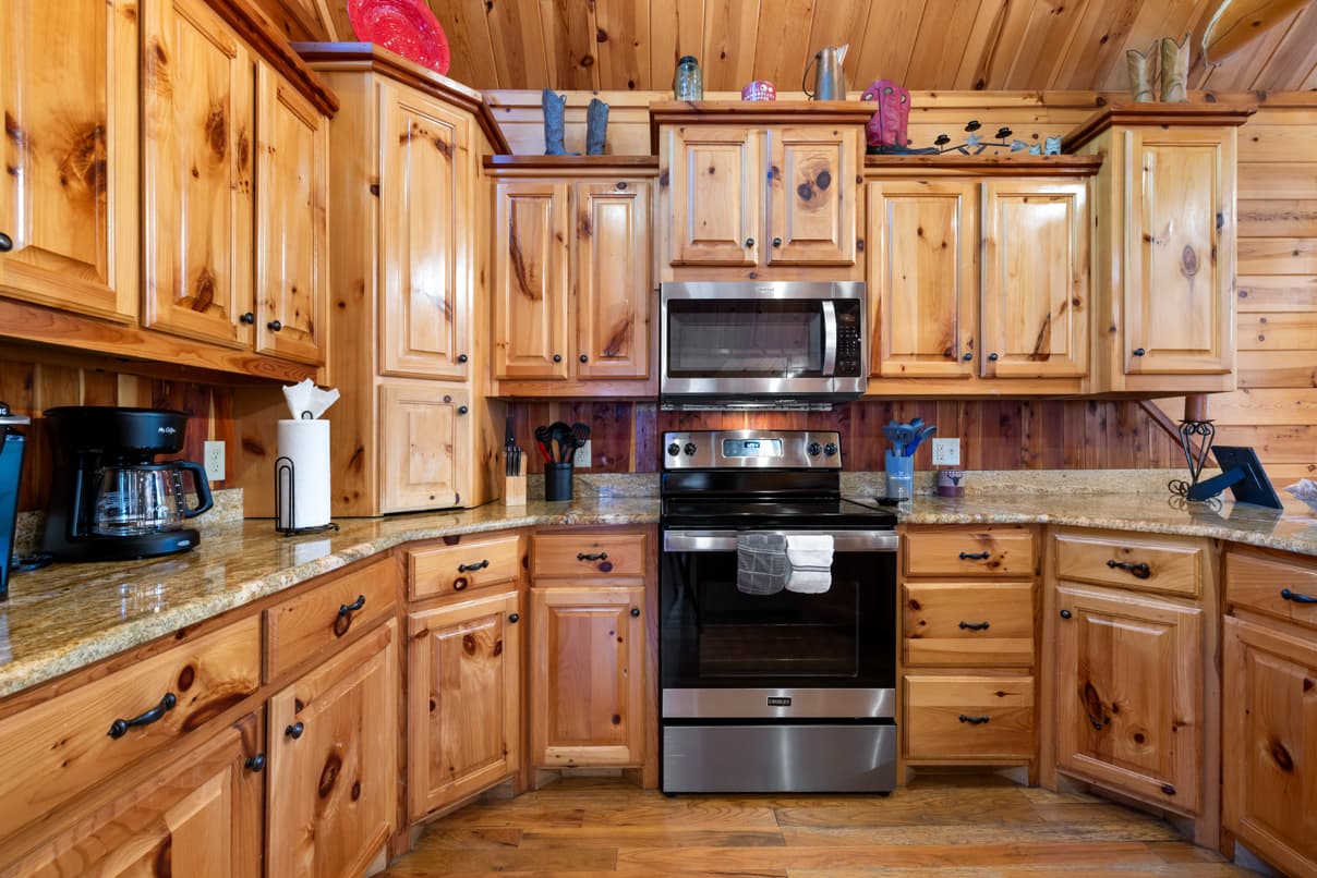 A cozy kitchen featuring wooden cabinets, stainless steel appliances, and granite countertops.