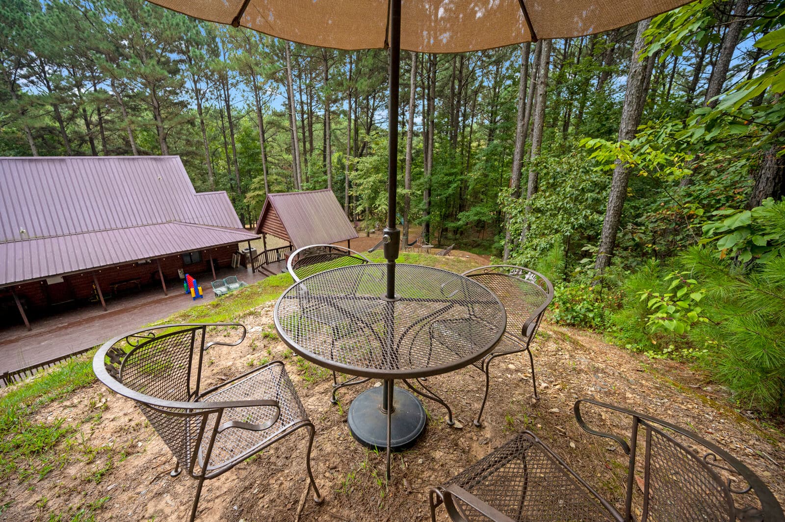 Table with umbrella on top of hill behind cabin