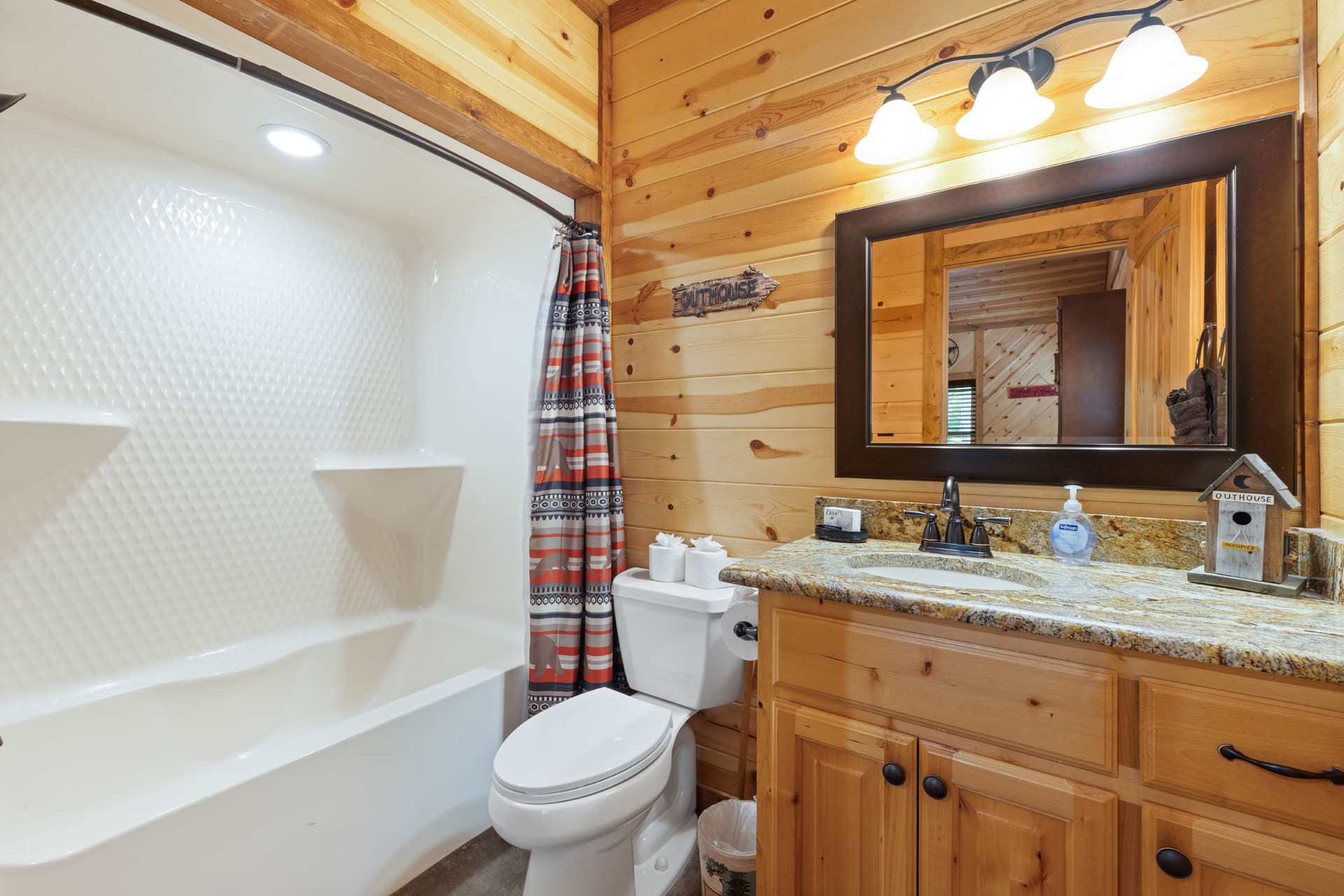 Bathroom with wooden walls, a shower, toilet, and a granite countertop vanity.