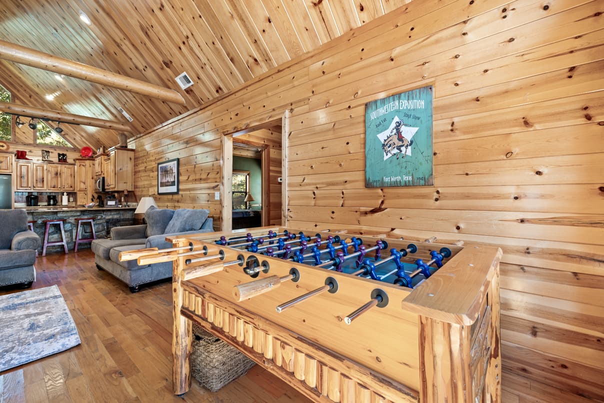 A rustic game room featuring a foosball table and cozy seating against a wooden backdrop.