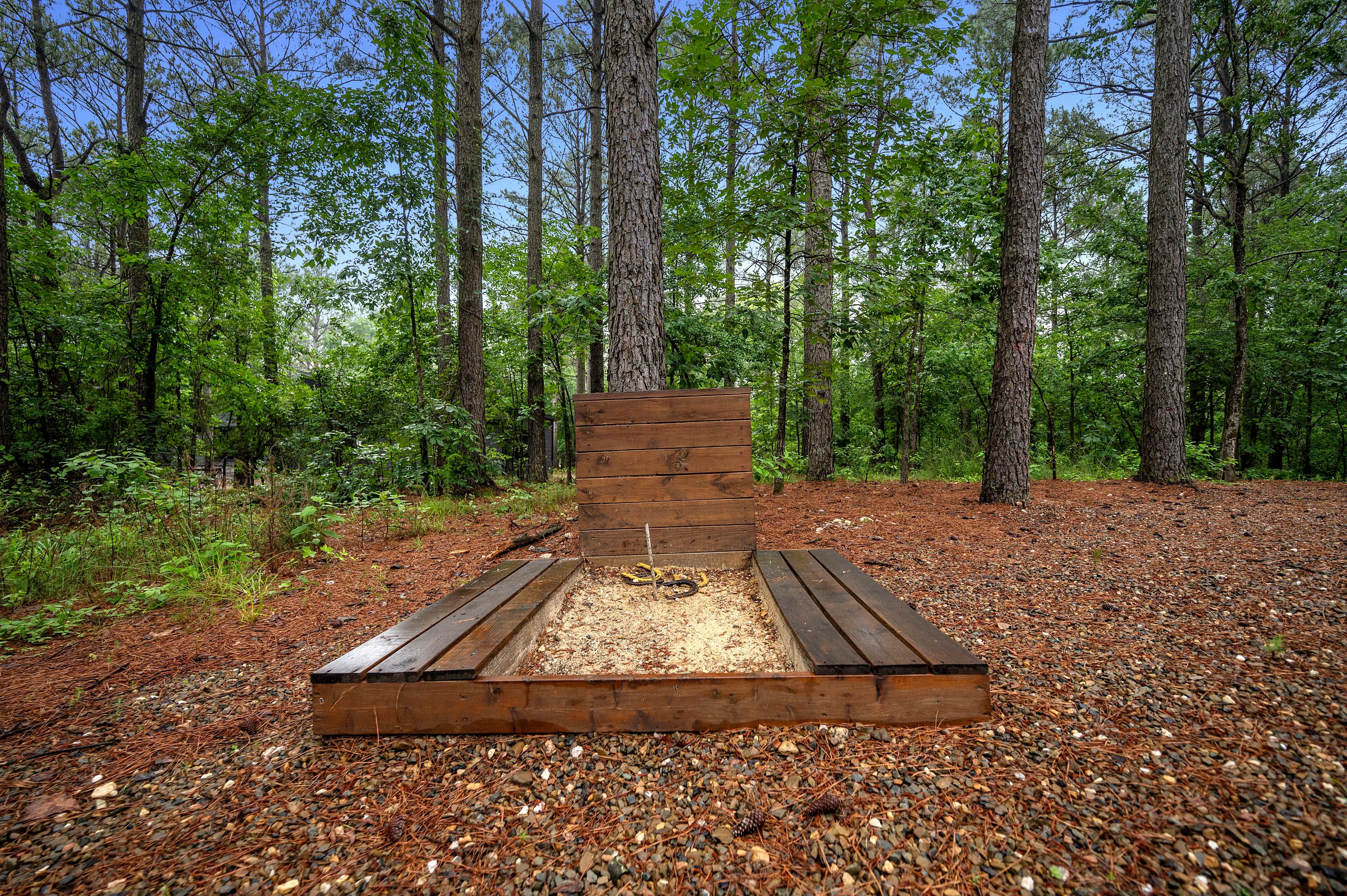 A wooden sandpit surrounded by trees in a forested area.