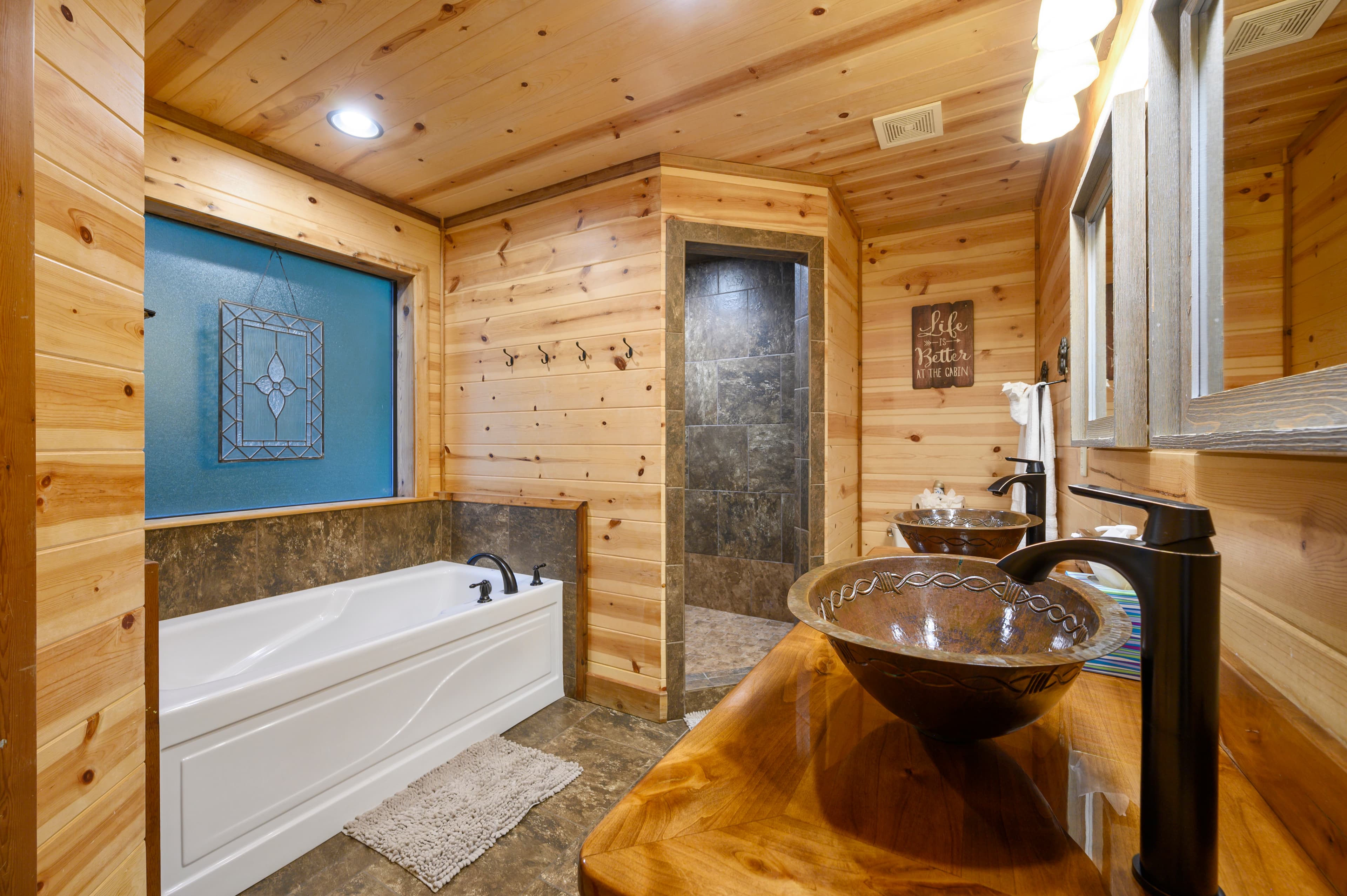 A cozy bathroom featuring a white bathtub, wooden accents, and a tiled shower.