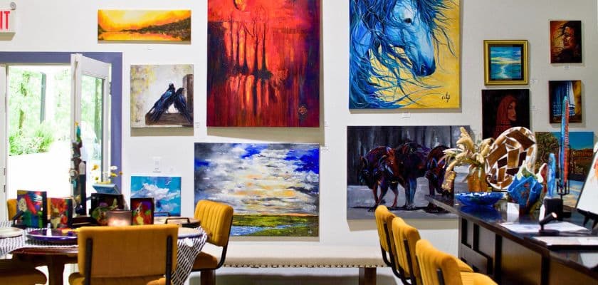 A vibrant art gallery featuring various paintings and a cozy seating area.