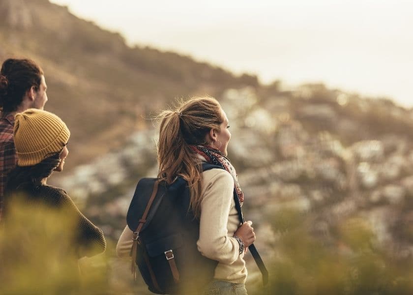 Three friends admire a scenic view from a hillside at sunset. Three friends admire a scenic view from a hillside at sunset.