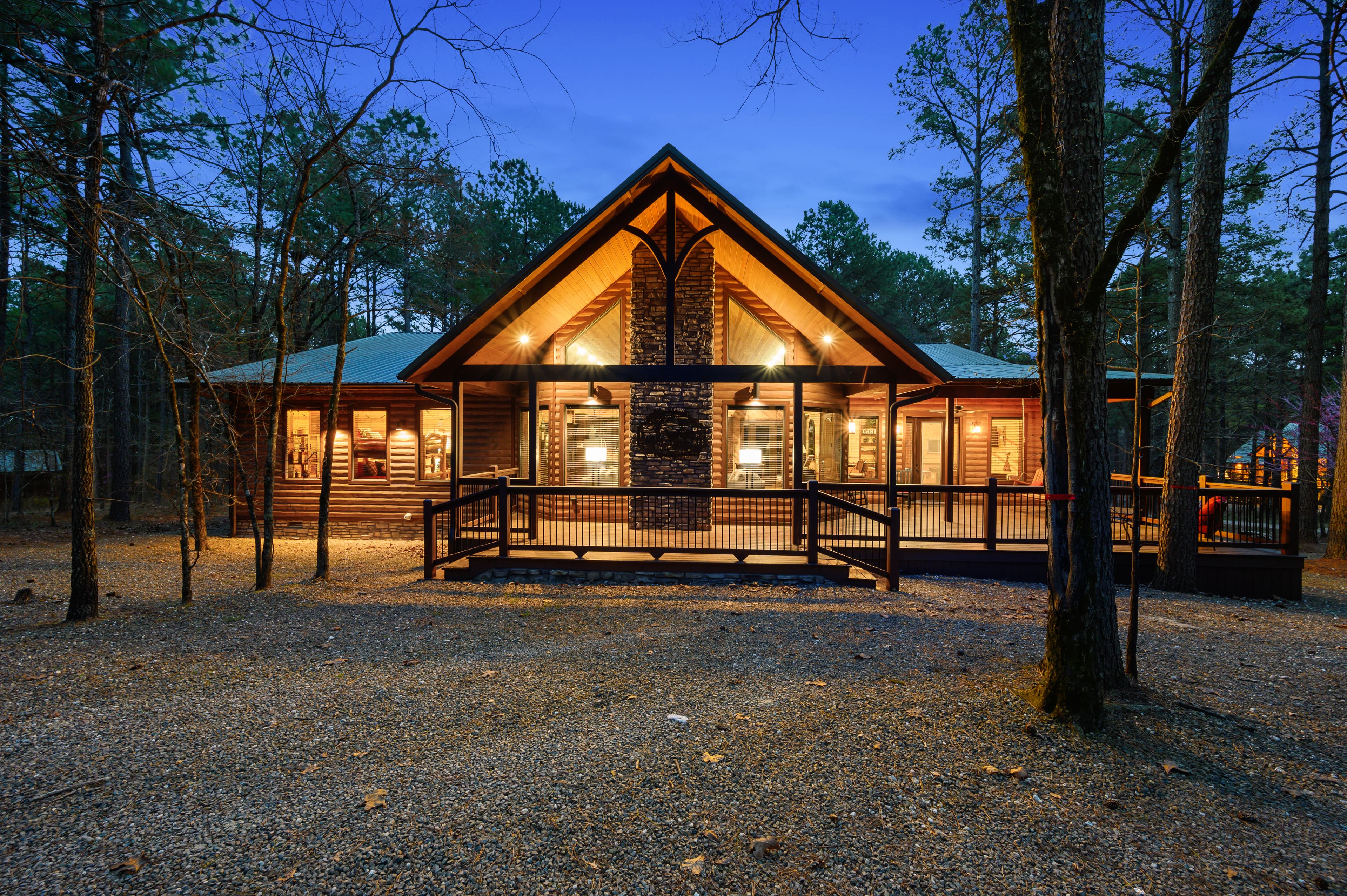 Front of log cabin with large gravel driveway