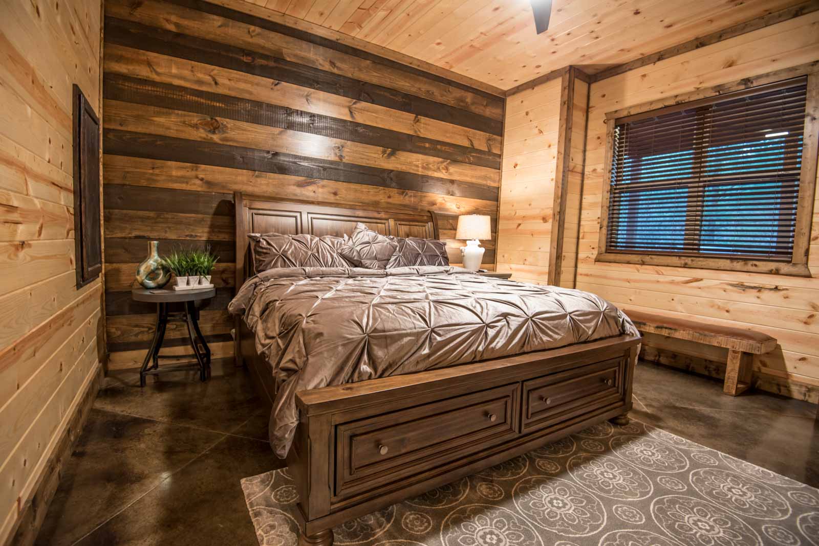 King downstairs bedroom with side tables, lamp, and a bench