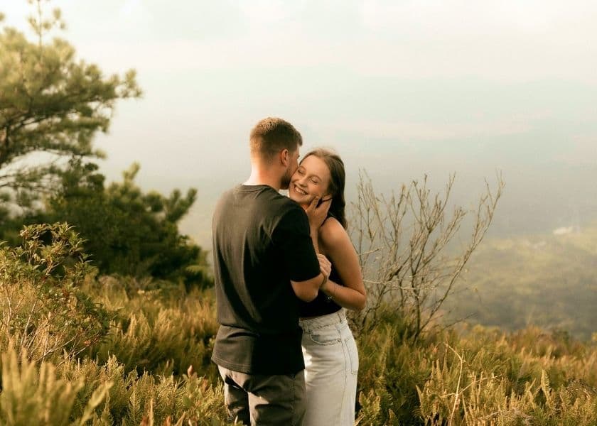 A couple embraces on a scenic overlook during a romantic getaway.