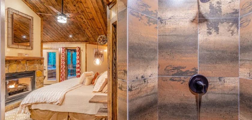 romantic bed, fireplace, and walk-in shower at kasmir cabin at beavers bend adventures