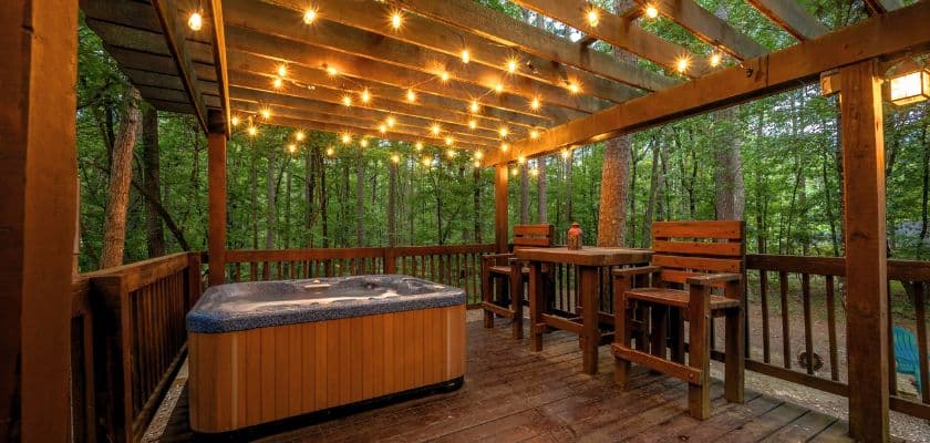 hot tub on wooden deck under twinkle lights at the copper pines cabin